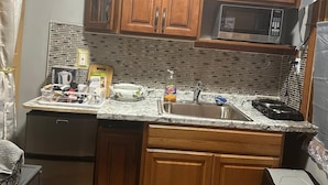 Cocina compacta con armarios de madera, microondas, fregadero y lavavajillas.