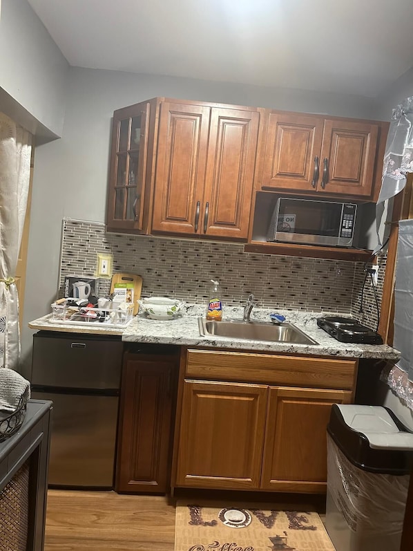 A compact kitchen with wooden cabinets, a microwave, a sink, and a dishwasher.