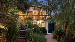 A two-story house with a balcony, surrounded by dense vegetation and a wooden staircase leading to the entrance. - Birds Nest of Topanga - Boho Chic and Minutes from Beach and Topanga Village!! (Topanga)