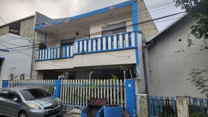A two-story building with a blue and white exterior, a balcony, and a fenced front yard. - OYO Life 93979 Gubeng Homestay Syariah (Surabaya)