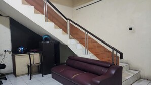 A room with a staircase, a sofa, a desk, and a chair. - OYO Life 93979 Gubeng Homestay Syariah (Surabaya)