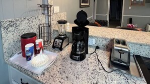 Ett kök med bänkskivor i granit, en kaffebryggare, en brödrost och en mixer. På väggen finns en skylt med texten: ”Här skapas köksmåltider och minnen – dygnet runt.”