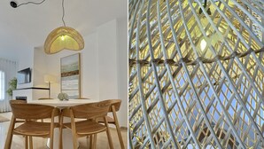 Un comedor con una mesa redonda y sillas de madera, un lámpara colgante y un televisor instalado en la pared.