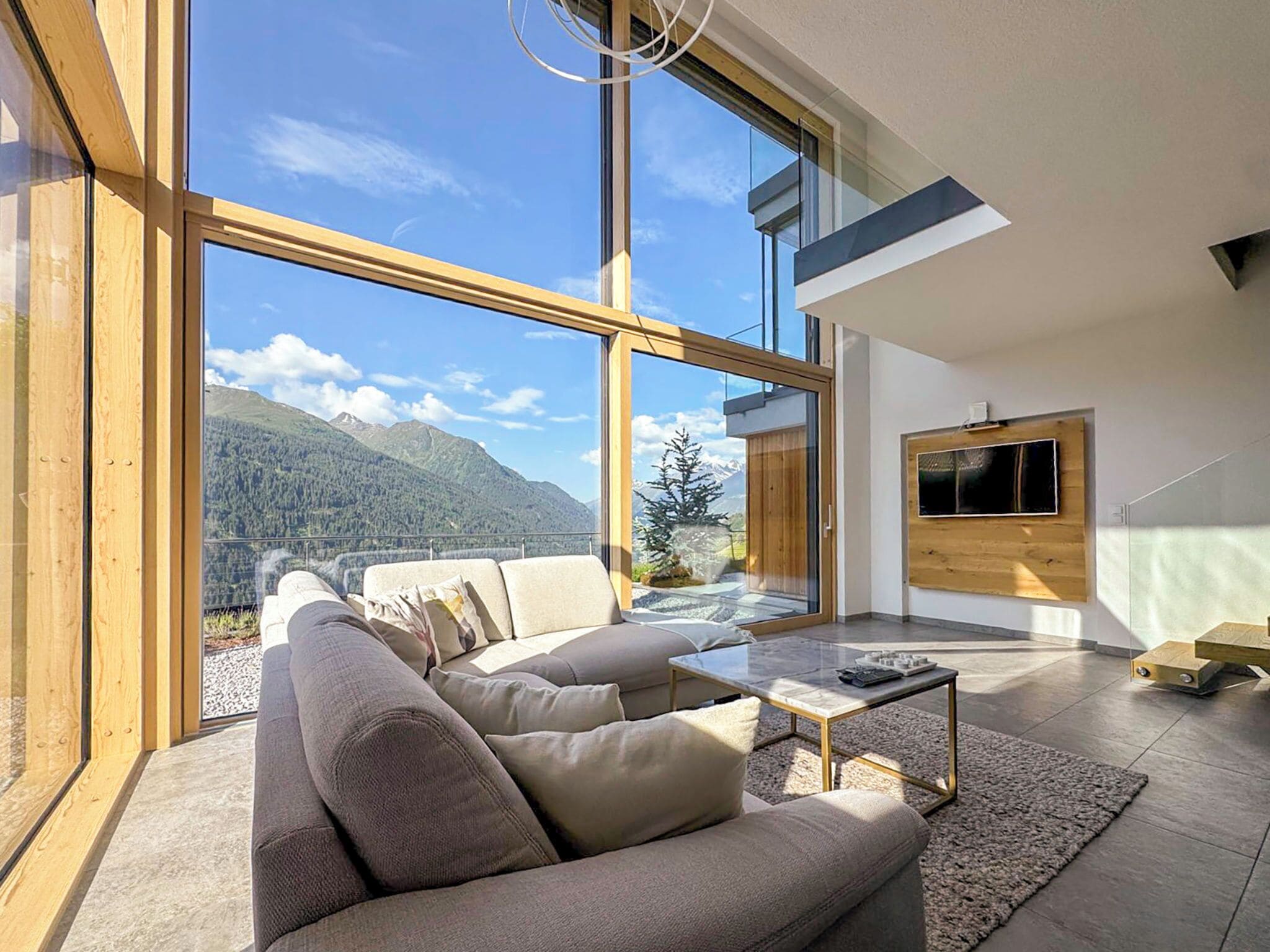Ein modernes Wohnzimmer mit großem Fenster, einer Couch, einem Couchtisch und einem wandmontierten Fernseher.