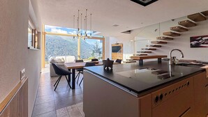 Une cuisine moderne dotée d’un îlot central, d’un coin repas offrant une vue agréable et d’un escalier menant à un niveau supérieur.