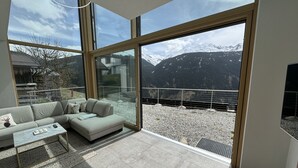 Un salon moderne doté d’une grande porte vitrée donnant sur un balcon avec vue sur les montagnes.