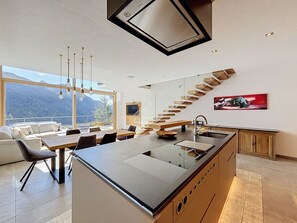 Cozinha moderna com ilha central, área de jantar com vista e escada de design exclusivo.