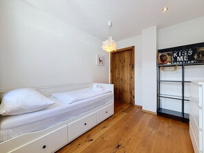 Un dormitorio con cama, una puerta de madera, una estantería blanca y una pared con un cartel.