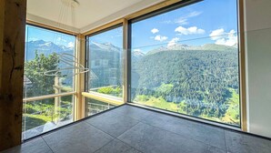 Une pièce dotée de grandes fenêtres offrant une vue sur les montagnes, d’un luminaire moderne et d ’un sol carrelé.