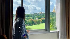 A room with a large window offering a view of a temple complex surrounded by greenery. - My Hotel Myanmar (Yangon)
