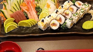 A sushi platter with various types of sushi and garnishes on a rectangular plate. - My Hotel Myanmar (Yangon)