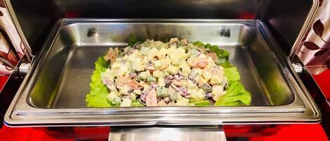 Un lavamanos de acero inoxidable con una ensalada sobre una hoja de lechuga verde.