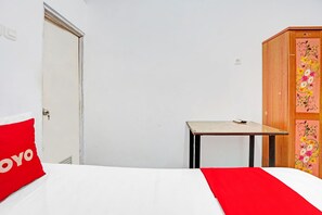 A bedroom with a bed, a small table, a wardrobe, and a door. - OYO 90790 Royale Nias (Surabaya)