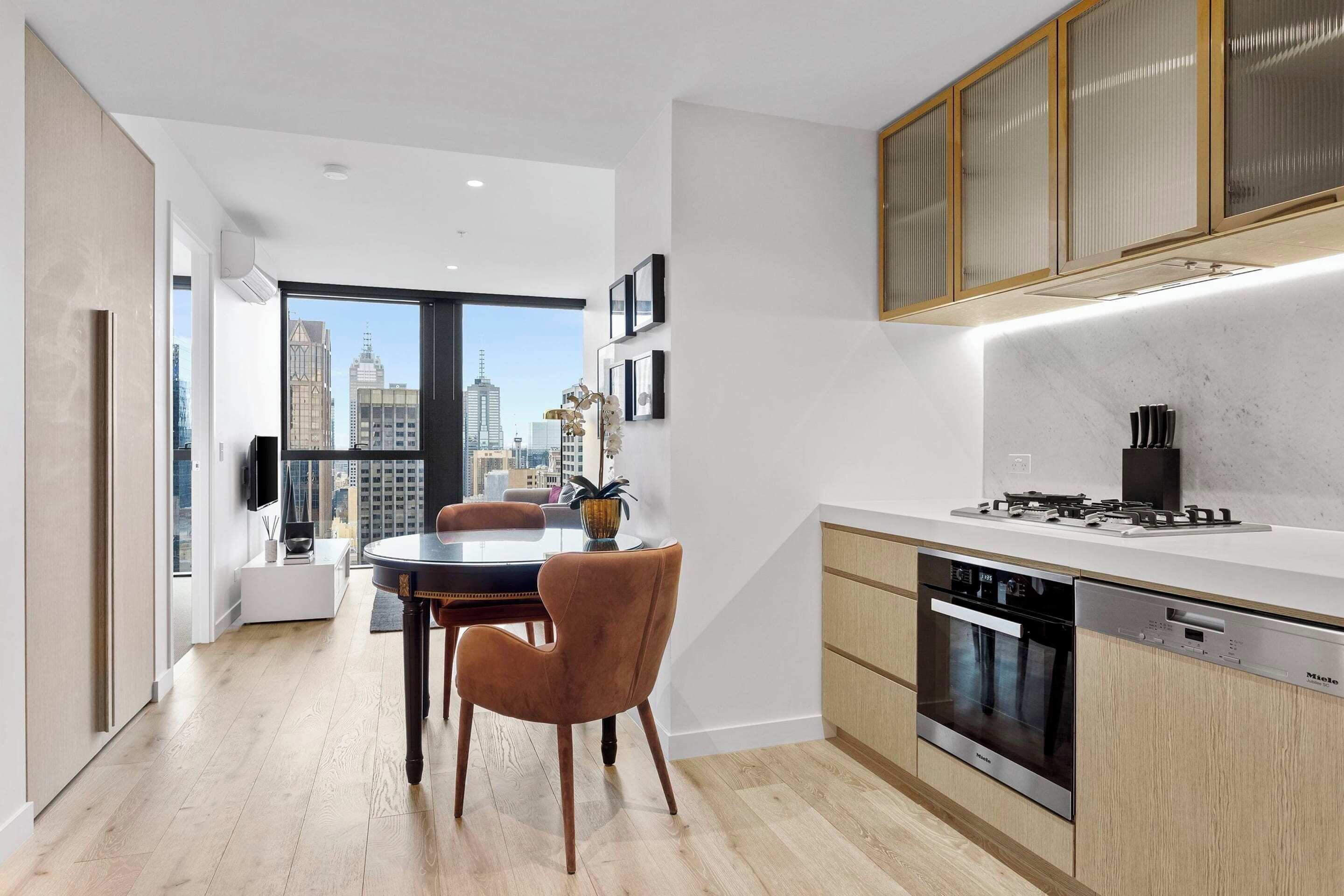 Une cuisine moderne avec un coin repas, de grandes fenêtres et une vue sur la ville.