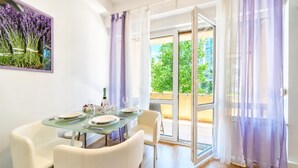 A dining area with a glass table, white chairs, and a view through glass doors to an outdoor space. - Lavanda Apartment With Terrace (Zagreb)