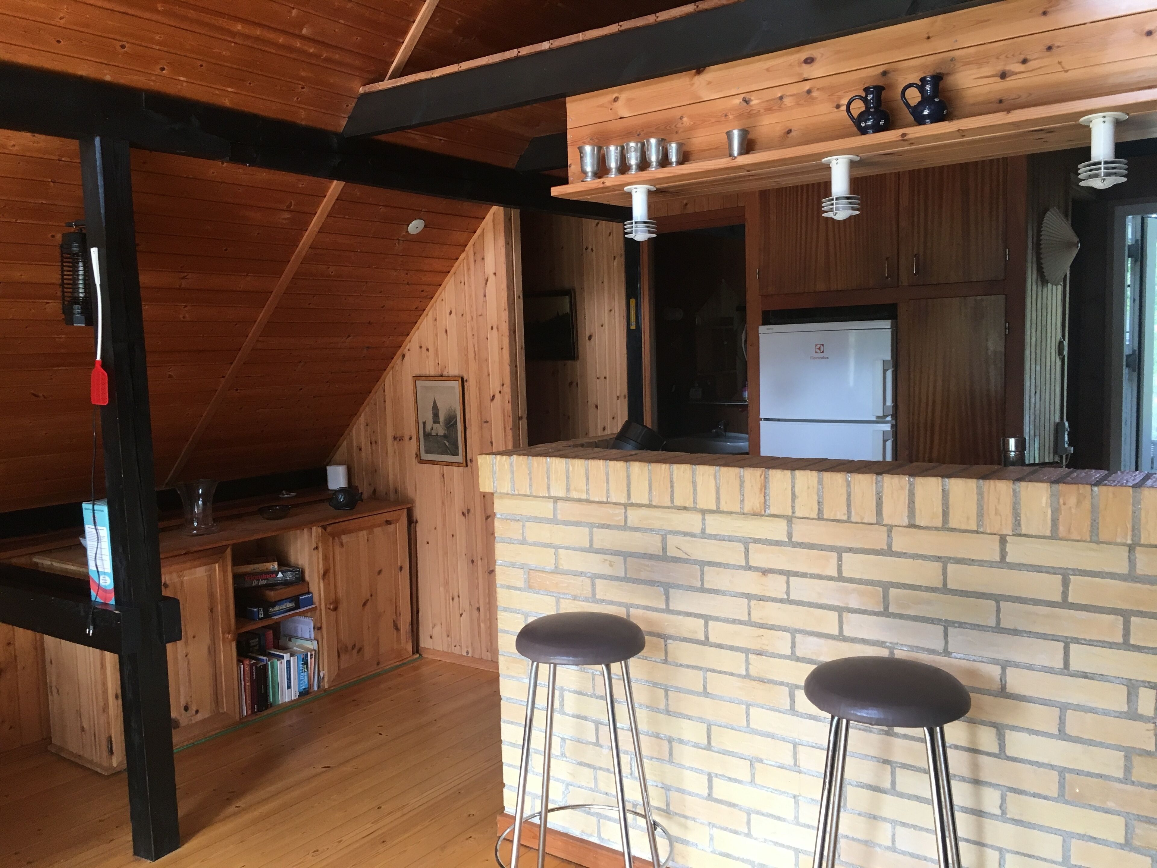 A cozy kitchen with wooden beams, a brick island, and two bar stools.