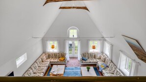 A loft-style room with a sloped ceiling, a large window, and a built-in seating area with a patterned sofa and a coffee table. - "Wandrath" - 2km from the sea by Interhome (Blåvand)