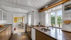 A modern kitchen with a large island, a sink, and a dining area with a yellow accent wall. - "Wandrath" - 2km from the sea by Interhome (Blåvand)