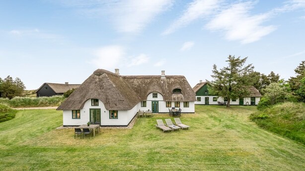 A thatched-roof house with a white exterior, a lawn with lounge chairs, and a clear sky. - "Wandrath" - 2km from the sea by Interhome (Blåvand)