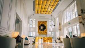Un'ampia hall con pavimento in marmo lucido, una reception e un grande cartello a parete con un monogramma.