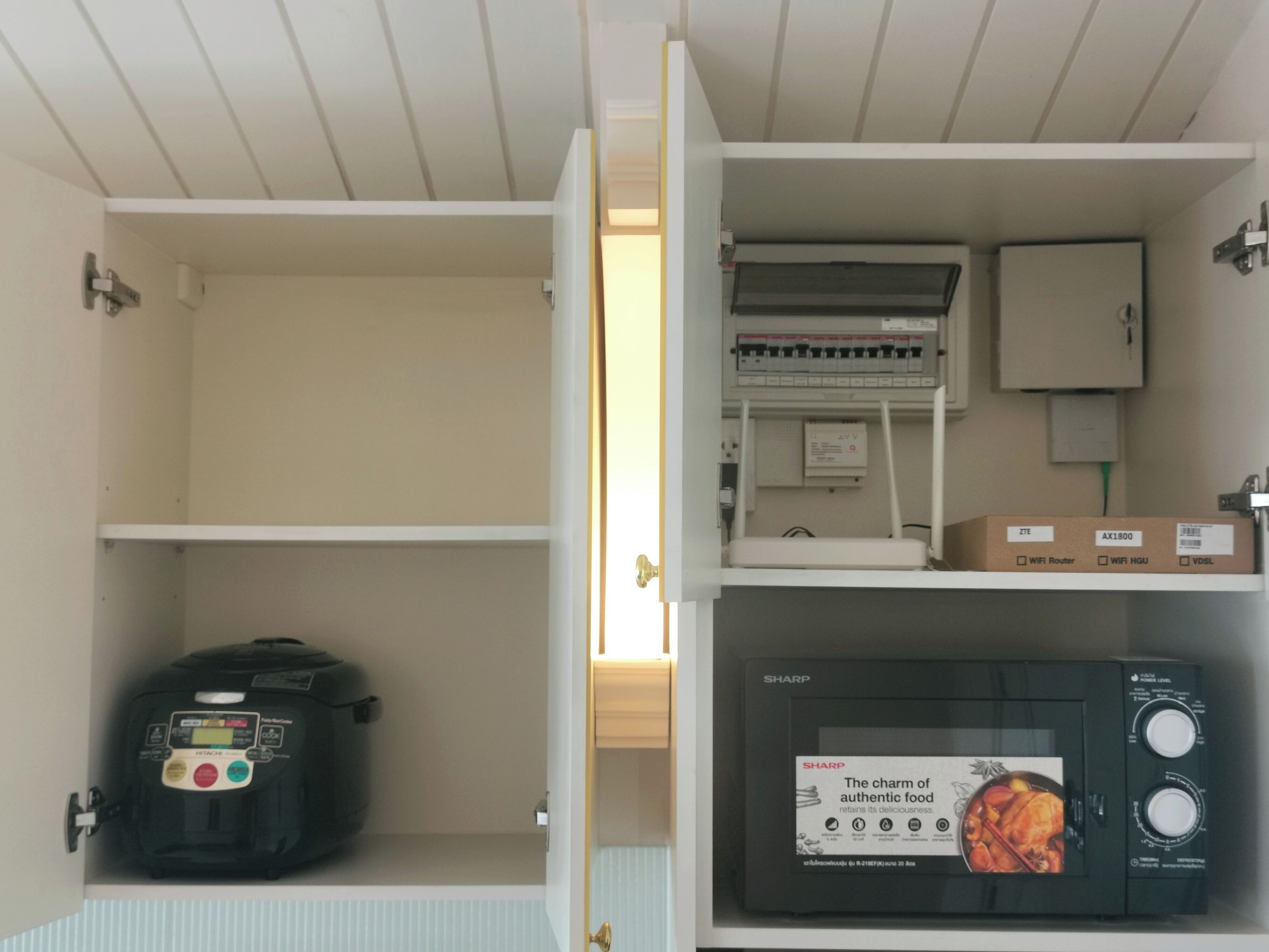 A kitchen with a microwave, a rice cooker, and a cabinet with a power strip.