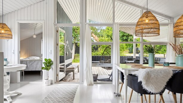 A spacious room with a large window, a dining area with a table and chairs, and a cozy seating area with a bench.