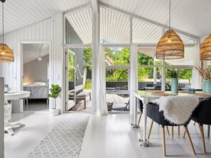 A spacious room with a large window, a dining area with a table and chairs, and a cozy seating area with a bench. - "Caro" - 900m from the sea by Interhome (Ebeltoft)