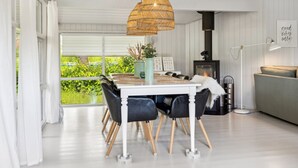 A modern dining area with a white table, black chairs, and a woven pendant light.