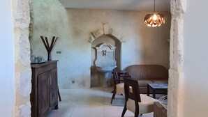 A rustic interior with a stone wall, a wooden cabinet, a dining table with chairs, and a hanging light fixture. - Village house in Ménerbes with a swimming pool and a dramatic view  (Ménerbes)