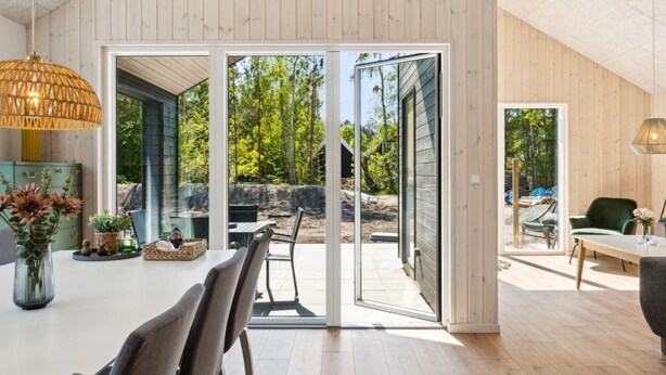 Un intérieur moderne comprenant un coin repas, une grande fenêtre et une vue sur l’extérieur.