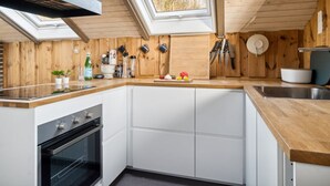 Een moderne keuken met houten wanden, een dakraam en een ingebouwde oven.