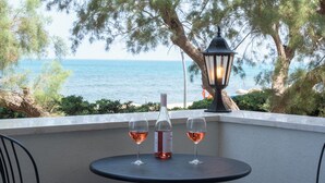 Une table avec une bouteille et deux verres de vin, donnant sur un plan d’eau bordé d’arbres et éclairé par une lampe.