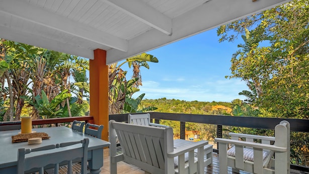 An outdoor patio with a table and chairs, surrounded by lush greenery and a clear view of the landscape. - San Lameer Villa 2849 (Southbroom)