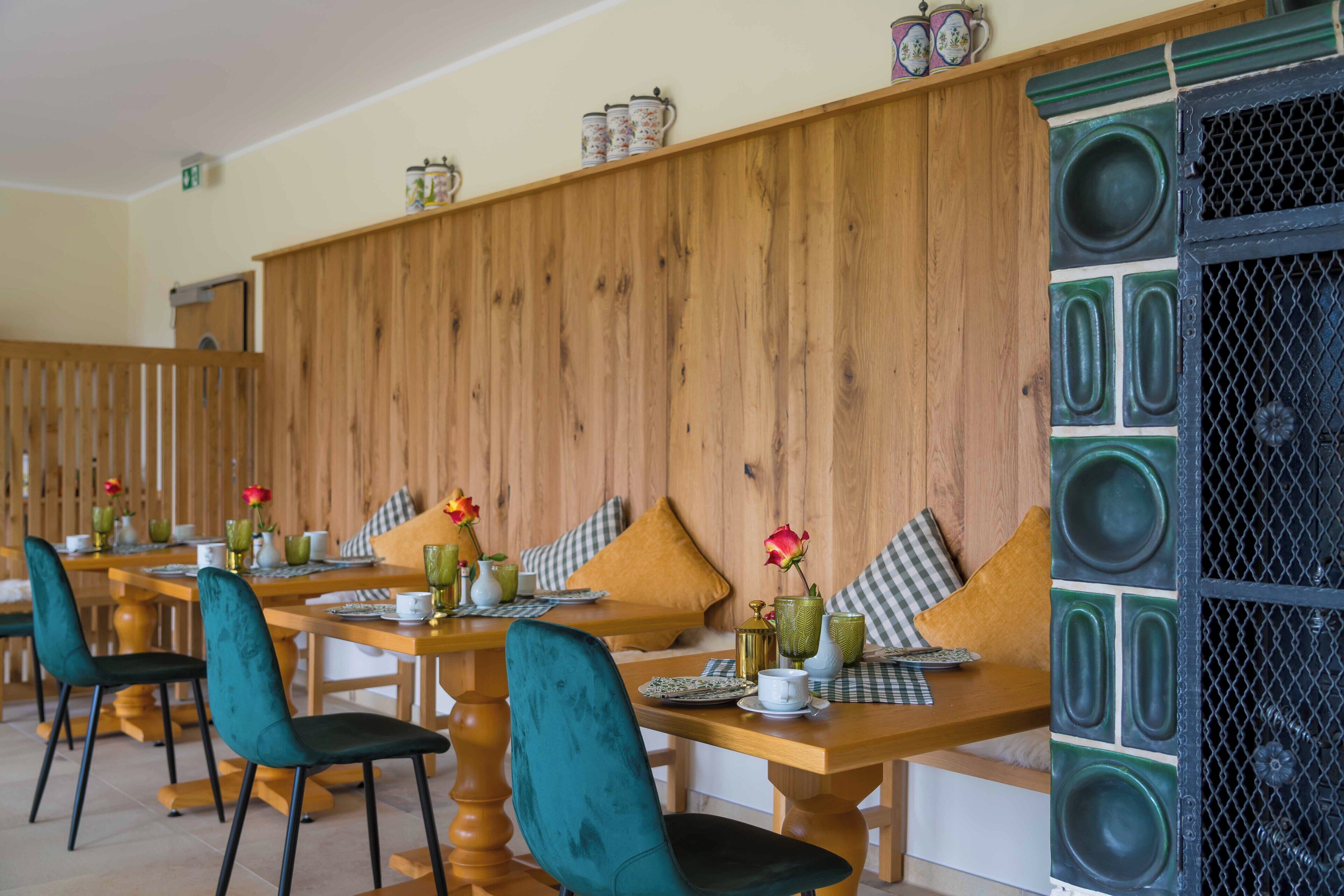 Un espace repas avec des tables en bois et des chaises de couleur turquoise, agrémenté de coussins à carreaux et de centres de table floraux.