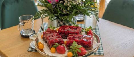 Een tafel met een bloemstuk, een schaal desserts en een glas water.