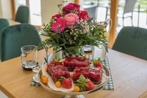 Une table ornée d’un arrangement floral, un plateau de desserts et un verre d’eau.