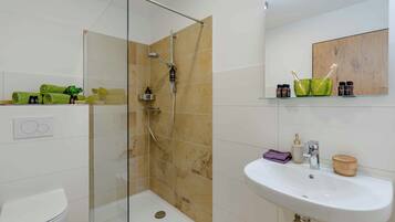 A bathroom with a glass-enclosed shower, a white sink, and a mirror above it.