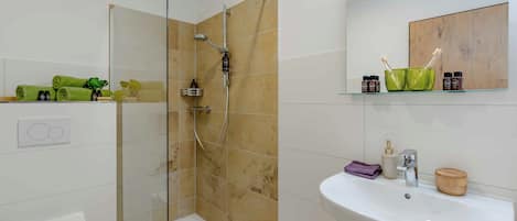 A bathroom with a glass-enclosed shower, a white sink, and a mirror above it.