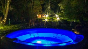 A hot tub in a garden at night with a building in the background. - Accogliente Appartamento, Animali Ammessi, Vicino Roma, Bracciano, Ladispoli (Lazio)
