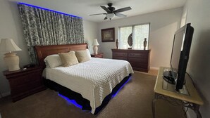 A bedroom with a bed, nightstands, a dresser, a ceiling fan, and a television.