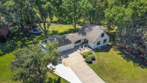 A single-story house with a covered patio, surrounded by trees and a well-maintained lawn.