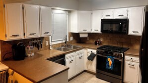 A modern kitchen with white cabinets, a black stove, a microwave, and a dishwasher.