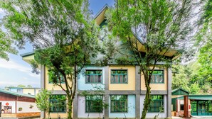 A multi-story building with a modern design, featuring large windows and a flat roof. - Green House (Puli)