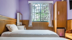 A hotel room with a bed, a wooden wardrobe, a small desk with a mirror, and a window with curtains. - Green House (Puli)