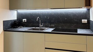 Une cuisine moderne avec un plan de travail noir, un évier en acier inoxydable et des armoires grises.