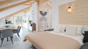 Ein modernes Schlafzimmer mit einem großen Bett, einem Holzkopfende und einem Essbereich mit Tisch und Stühlen.