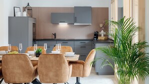 A modern kitchen with grey cabinets, a dining area with a table set for four, and a large green plant.