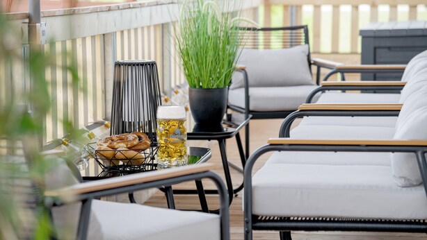 A deck with outdoor seating, a grill, and a potted plant.