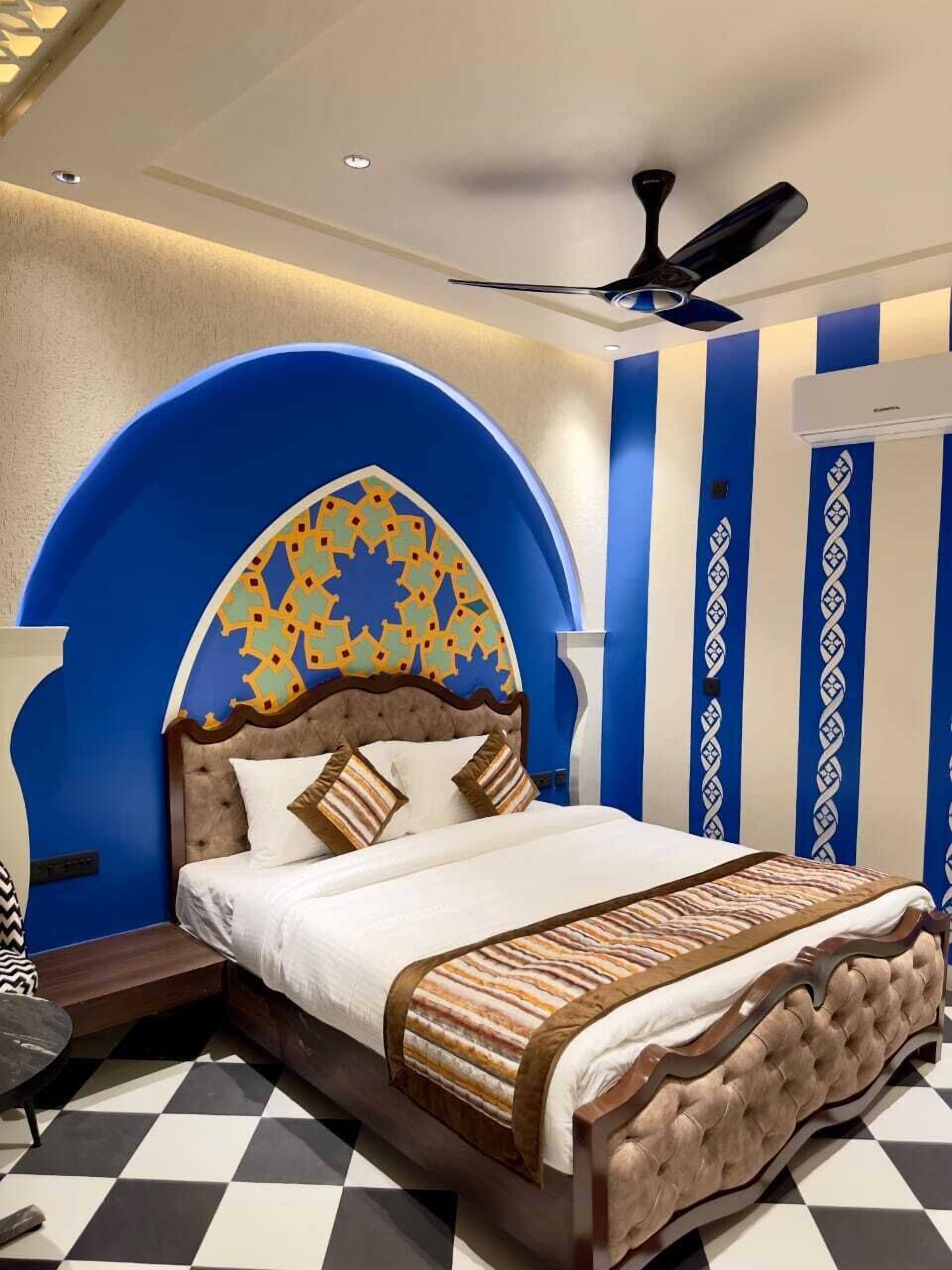 A bedroom with a large bed, a ceiling fan, and a patterned wall.