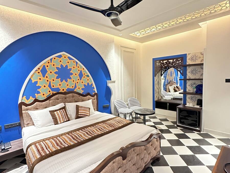 Una habitación de hotel moderna con una cama grande, un ventilador de techo, una pared con diseño y un suelo a cuadros.